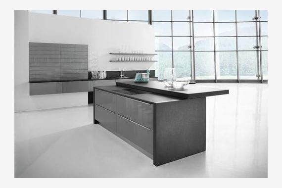 Moderne Designküche mit großer Kücheninsel, dunkler Granit-Arbeitsplatte aus Naturstein und großzügiger Fensterfront