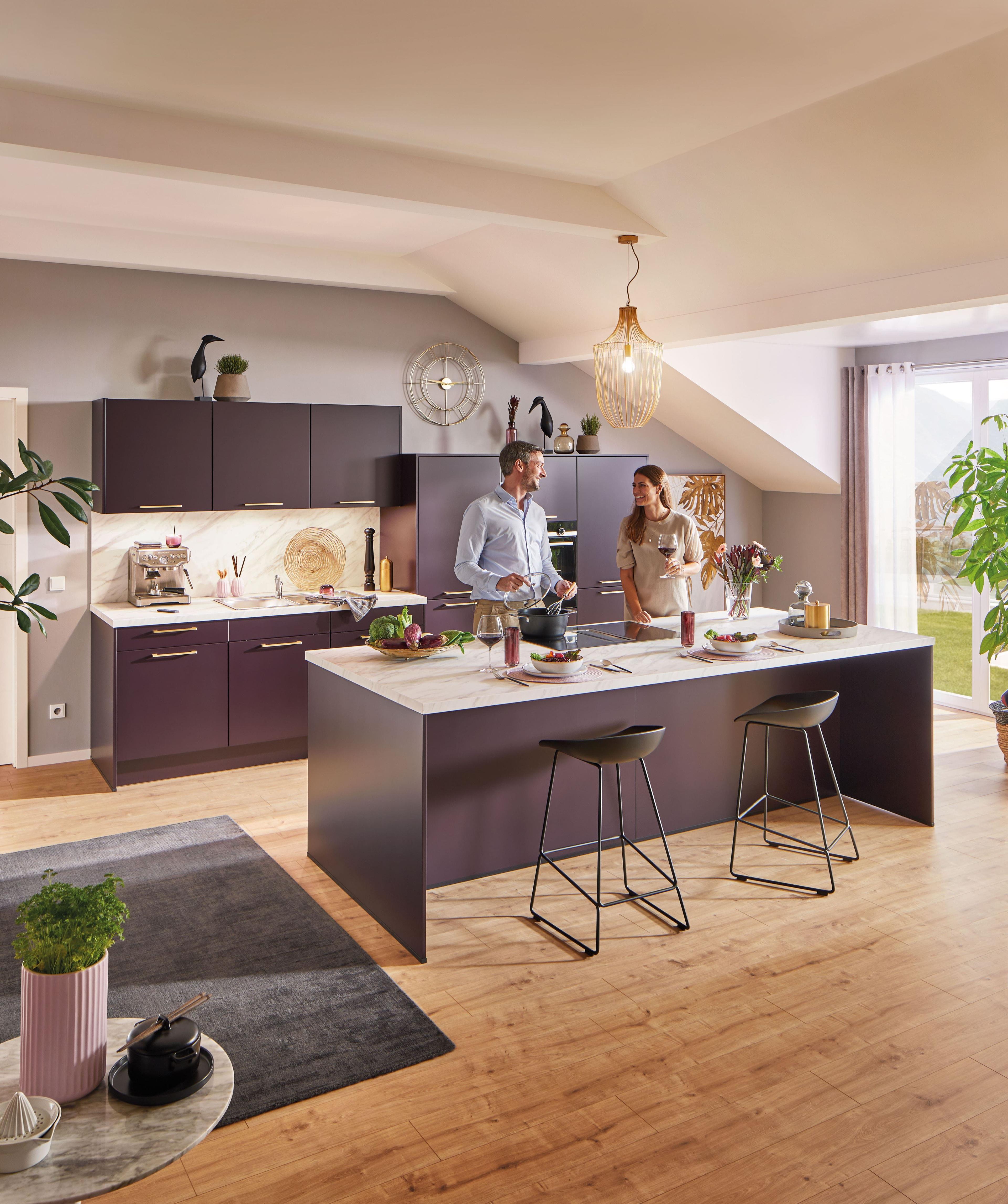 Häcker Küche in dunklem Brombeerton mit kleiner Kücheninsel und heller Arbeitsplatte in Marmoroptik