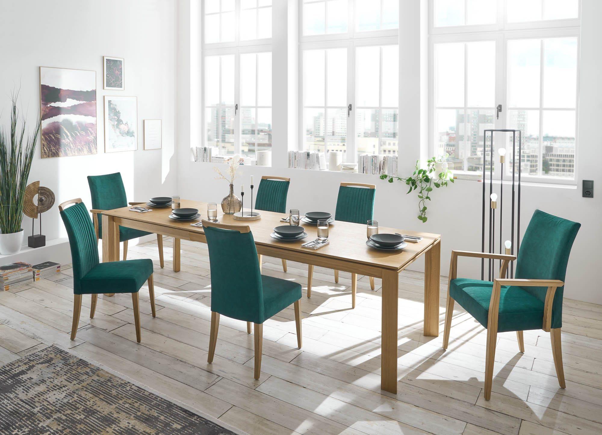 Catera Essgruppe in Eiche mit petrolgrünen Polsterstühlen und Armlehnstuhl, gedeckter Tisch in hellem Loft mit Stadtpanorama