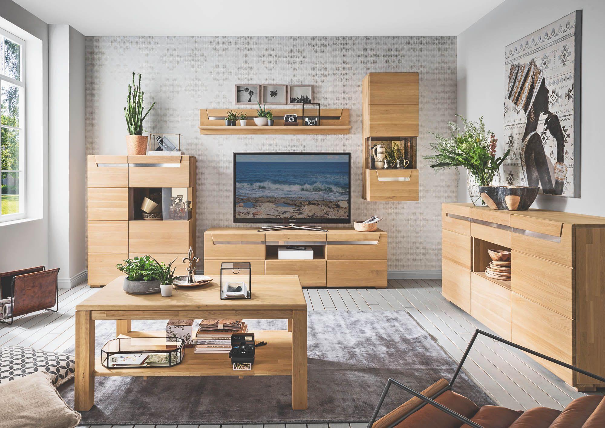 Stilvolles Wohnzimmer mit kompletter Wohnwand in Holzoptik: TV-Board mit Fernseher, Wandregal, Vitrine/Hängeelement und großes Sideboard, ergänzt durch Couchtisch und wohnliche Dekoration im hellen Raum