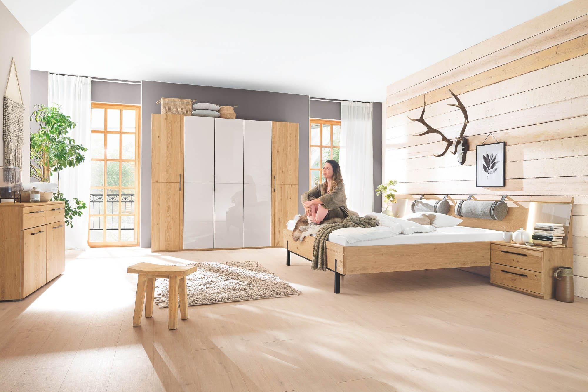 Rauch Cadore Schlafzimmer in Eiche Artisan mit Doppelbett, Drehtürenschrank in Weiß-Eiche-Kombination und Kommode in gemütlichem Landhausstil mit Holzwand-Akzent