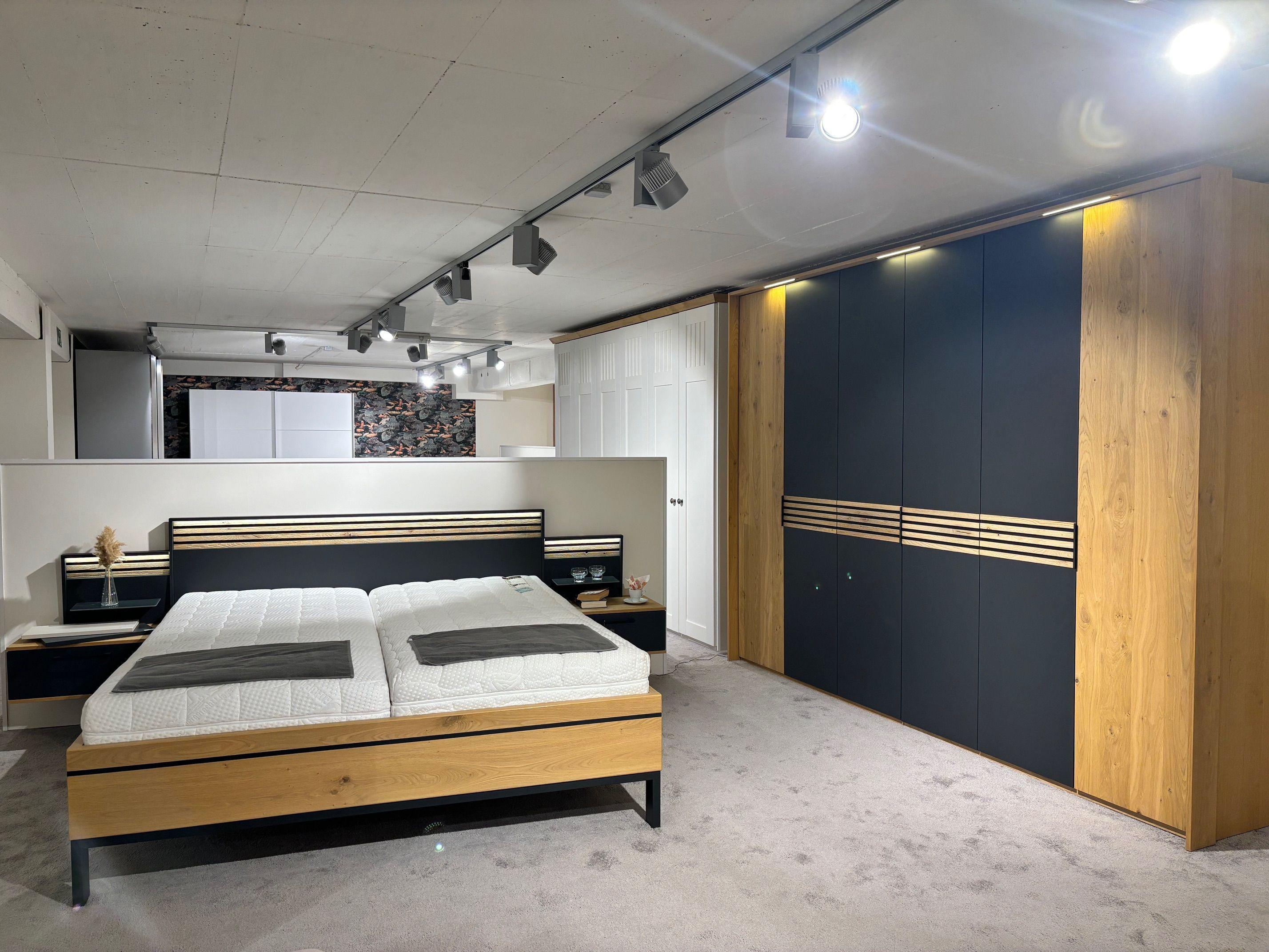 Schlafzimmer-Set in Anthrazit und Eiche mit Doppelbett, Nachttischen und großem Drehtürenschrank mit Holzlamellen-Dekor.