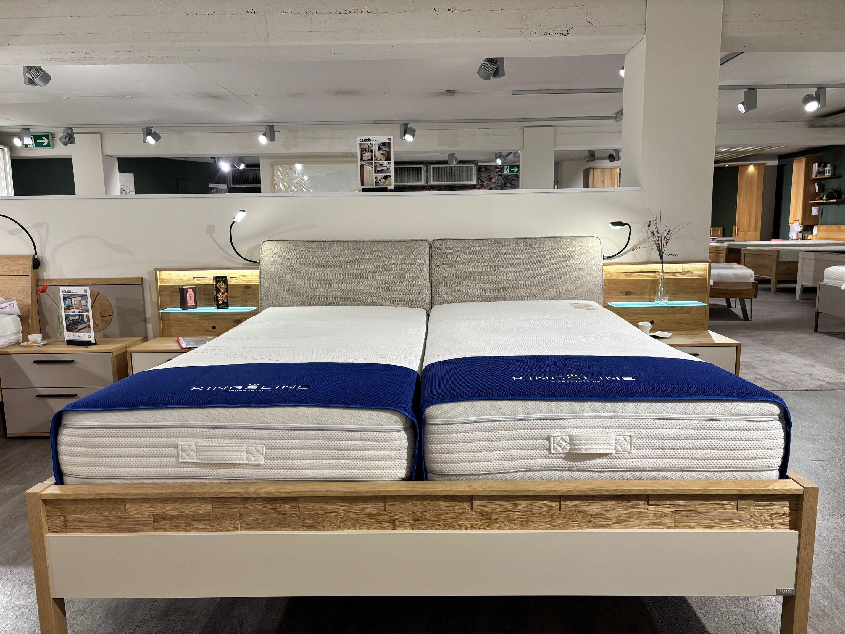 Eiche-Doppelbett mit Kingsline-Matratzen und gepolstertem Kopfteil, LED-beleuchtete Nachttische, im Möbelhaus-Showroom.