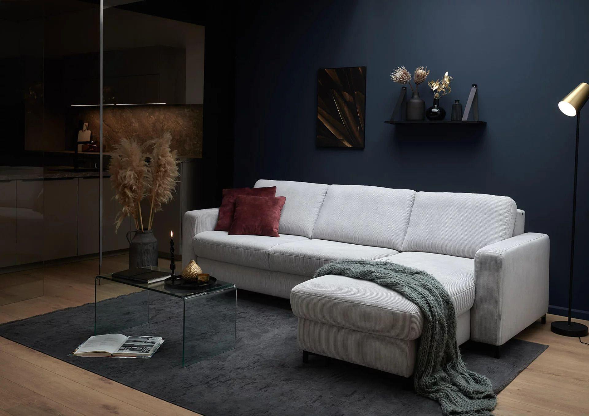 Hellgraues Hukla Ecksofa mit Recamiere in gemütlicher Wohnatmosphäre mit dunkler Wand und Dekoration.