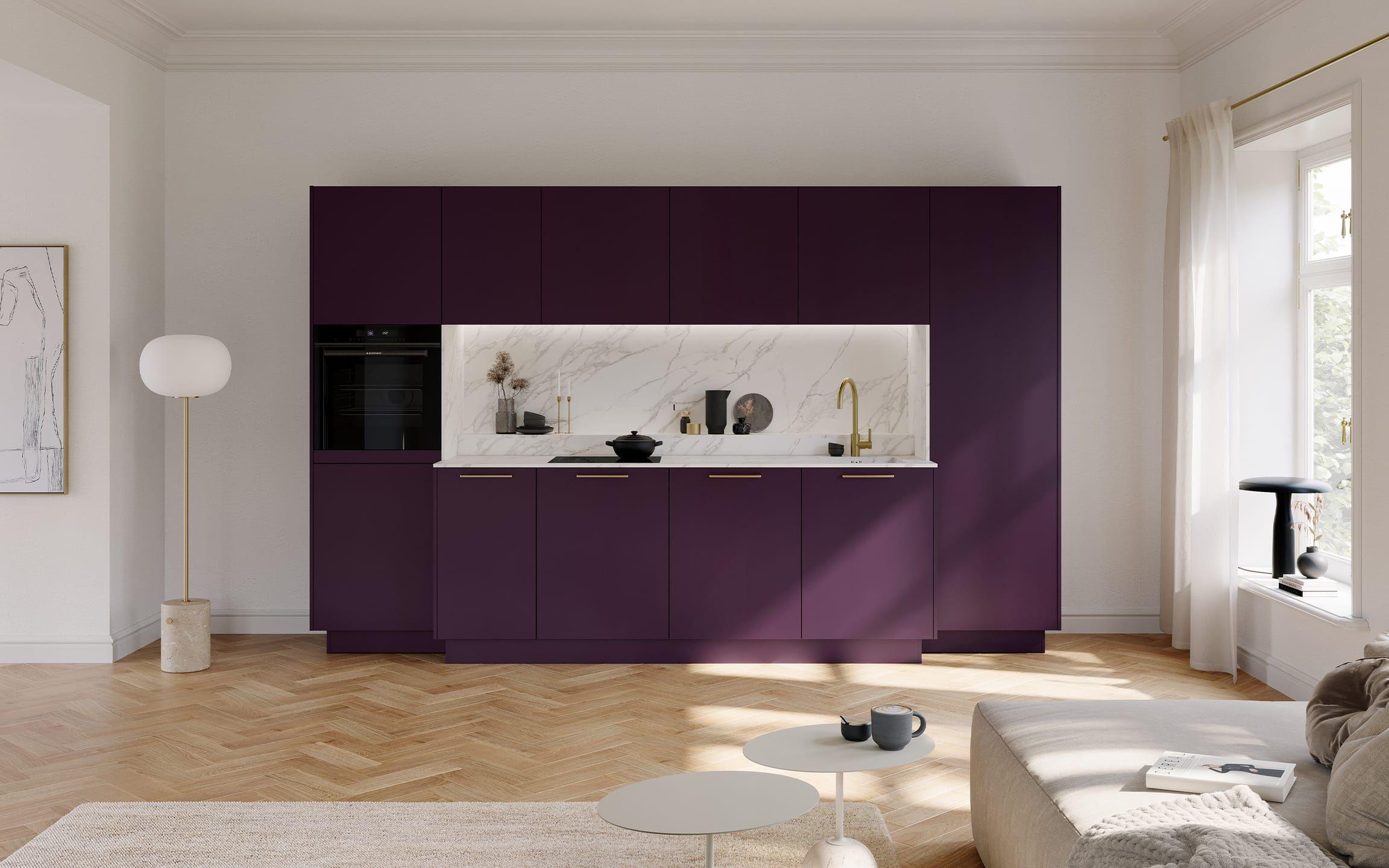 Häcker Küche Porto GL Selection Blackberry – elegante, griffbetonte Einbauküche in dunklem Violettton mit goldenen Griffen, integrierter Nischenbeleuchtung, Rückwand in Marmoroptik sowie Spüle und Armatur in Goldoptik im hellen Wohnraum